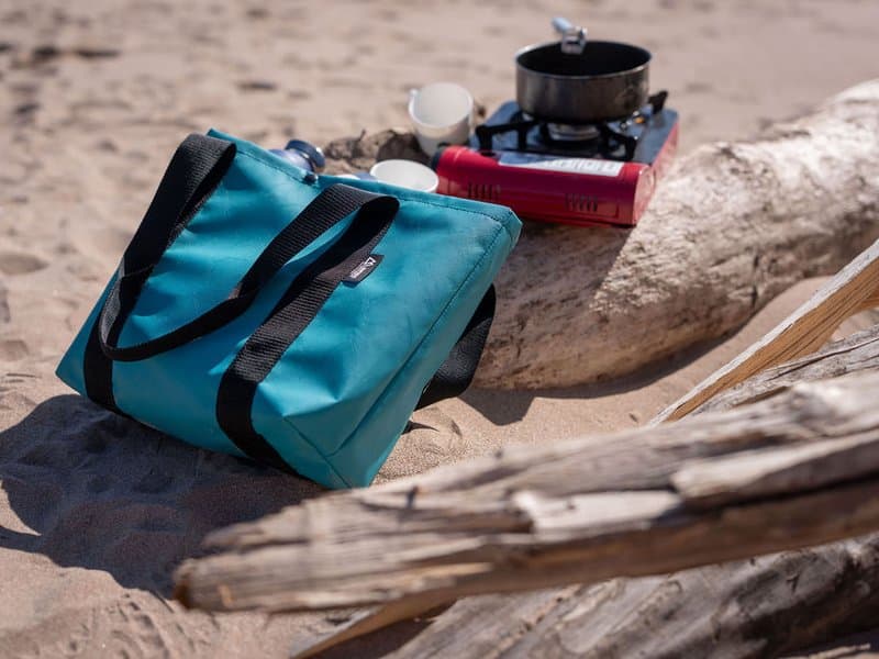 Teal Montrose bag with camp stove on driftwood